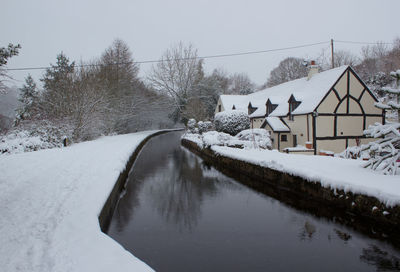 Snow covered road by trees against sky
