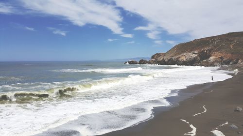 Scenic view of beach against cloudy sky