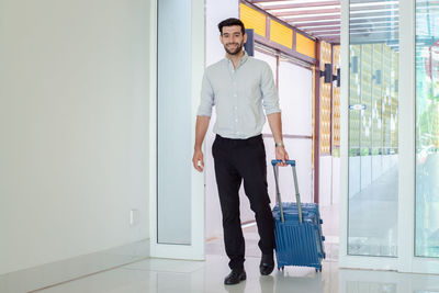 Full length portrait of young man standing against wall