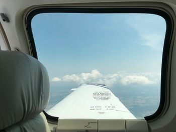 Airplane wing against sky seen through glass window