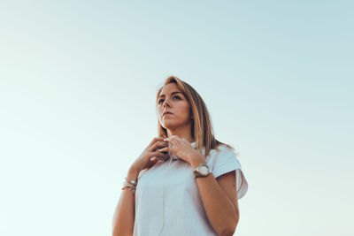 Low angle view of young woman against sky