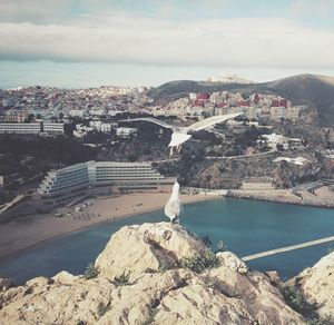 View of city by sea against cloudy sky