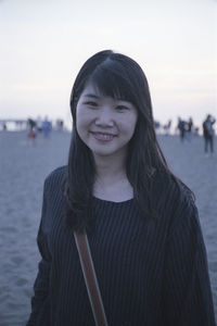 Portrait of young woman standing against sea