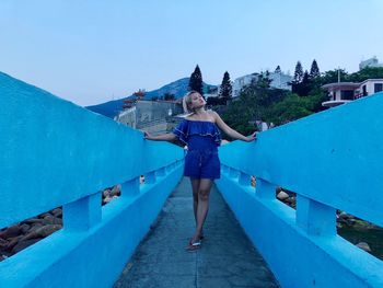 Full length of woman standing against blue sky