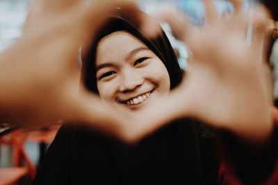 Portrait of smiling teenage girl seen through heart shape