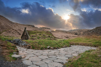 Beautiful turf house and geothermal hot spring in hrunalaug against cloudy sky