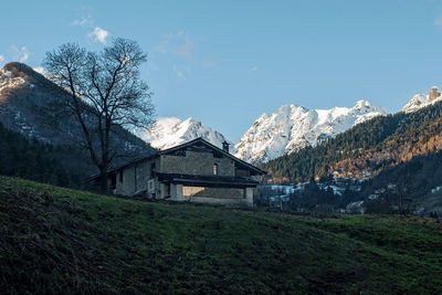 Houses on field by mountain against sky