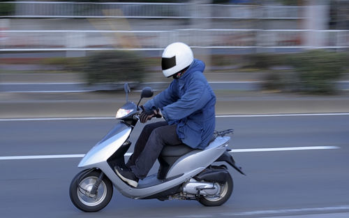 Side view of man riding motorcycle on road