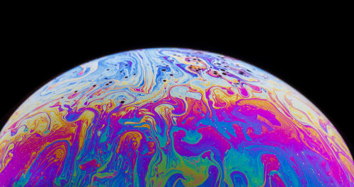 Close-up of multi colored bubbles over black background