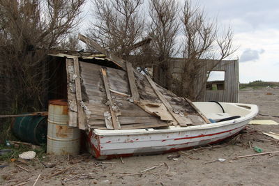 Abandoned boat on land against sky