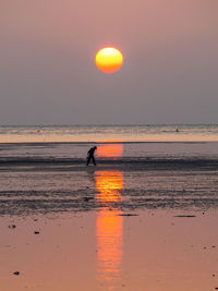 Silhouette person on beach against sky during sunset