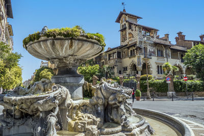 Statue of fountain against building in city