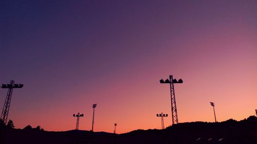 Low angle view of silhouette pylons against clear sky