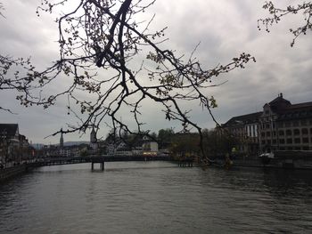 Bridge over river by buildings in city against sky