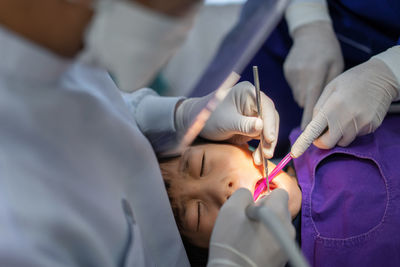 Hand of doctor dentist is working on the teeth of asian little kid 6 year patient in dental clinic