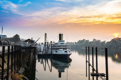 Boats moored at harbor against sky during sunset