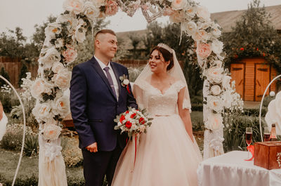 Portrait of bride and bridegroom standing against trees