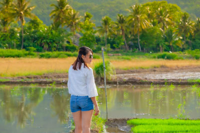 Full length of woman standing by lake