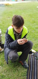 Rear view of boy holding mobile phone in field