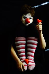 Midsection of woman holding red berries against black background