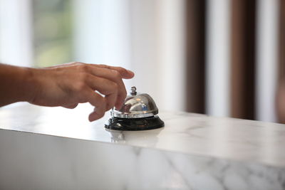 Midsection of person holding clock on table