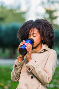 Young woman drinking while standing outdoors