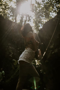 Rear view of woman standing in forest