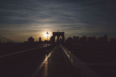 Railway bridge in city against sky during sunset