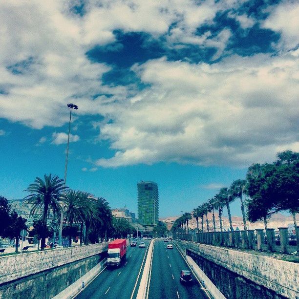 transportation, the way forward, sky, road, cloud - sky, built structure, car, architecture, city, tree, diminishing perspective, land vehicle, building exterior, cloudy, road marking, street, vanishing point, mode of transport, cloud, street light