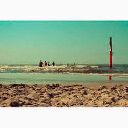 People on beach against clear sky