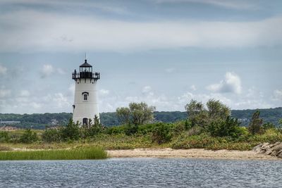 Lighthouse by sea against sky