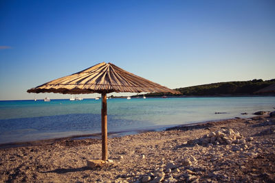 Lifeguard hut on beach against clear blue sky