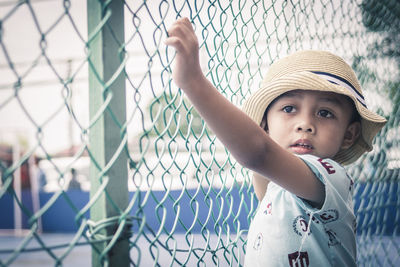Close-up of boy looking away while standing by fence
