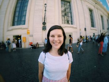 Portrait of smiling woman standing against building in city