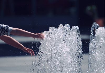 Cropped hands of person touching fountain