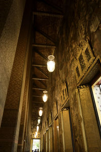 Low angle view of illuminated light bulbs hanging on building