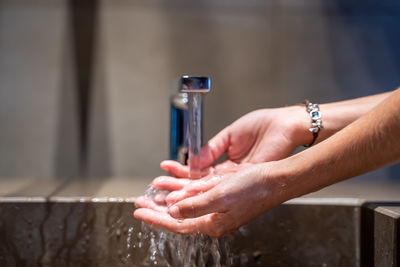 Close-up of woman hand holding faucet in water