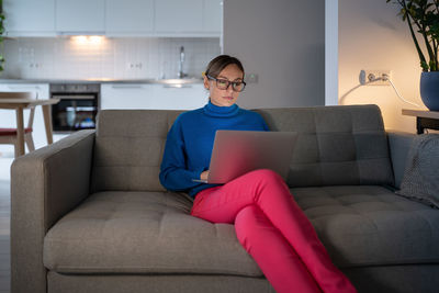 Young businesswoman in glasses and blue sweater works preparing for important meeting at home