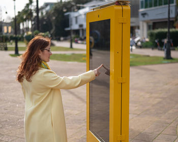 Side view of young woman looking away while standing in city