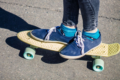 Low section of woman skateboarding on road