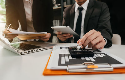 Midsection of businessman using laptop on table