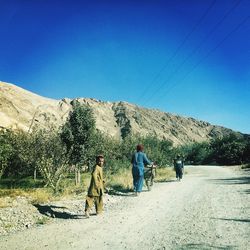 Rear view of people on mountain range against clear blue sky