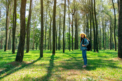 Full length portrait of woman standing at forest