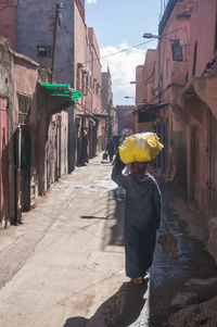 Rear view of man walking on street amidst buildings