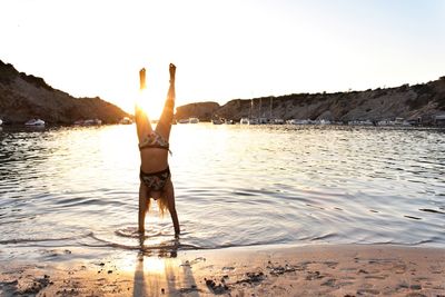 Man standing on beach against sky during sunset