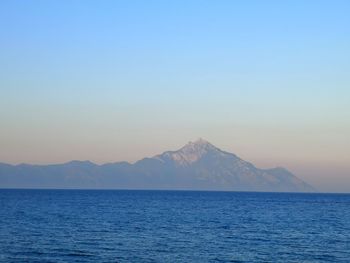 Scenic view of sea and mountains against clear blue sky