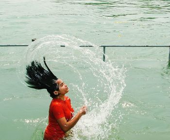 Side view of woman splashing water in river