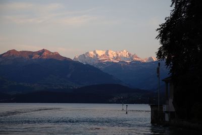 Scenic view of sea and mountains against sky during sunset