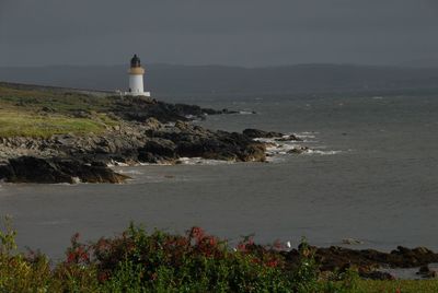 Lighthouse by sea against sky