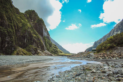 Scenic view of river flowing amidst mountains against sky